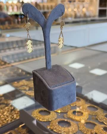 Gold earrings on stands inside a glass display case